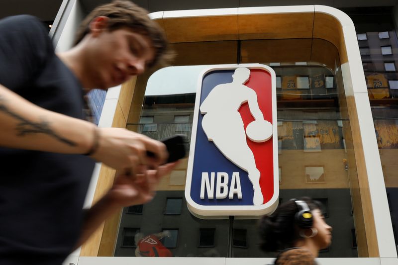 The NBA logo is displayed as people pass by the