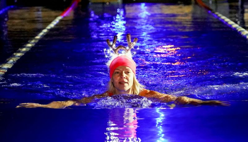 Woman wearing a Christmas decorations headwear swims during a largest
