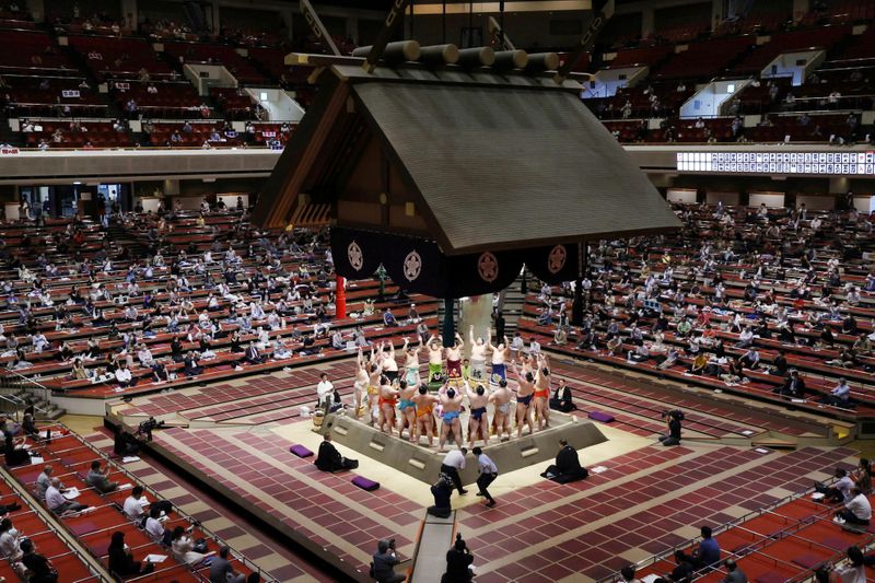 Spectators are seen as sumo wrestlers hold a ring-entering ceremony