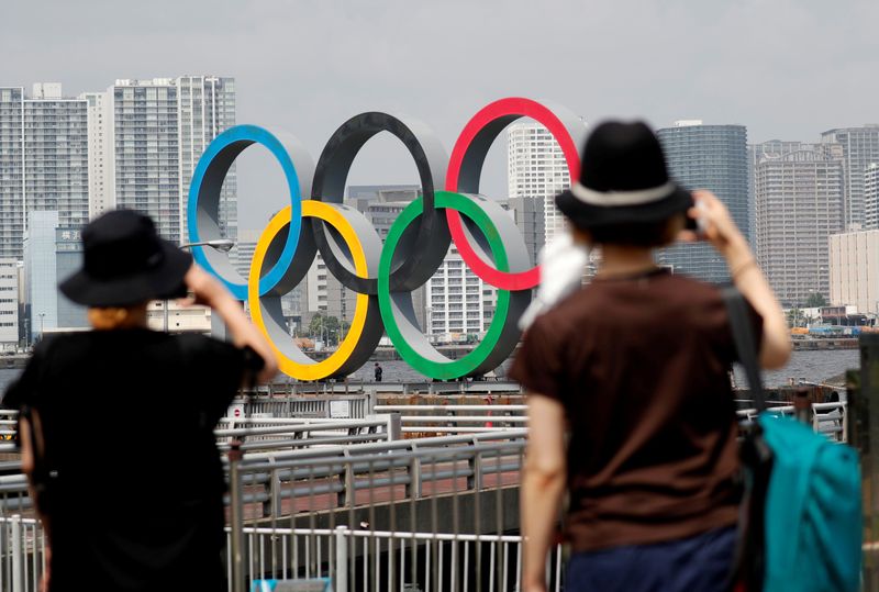 FILE PHOTO: Women look at the giant Olympic rings, which