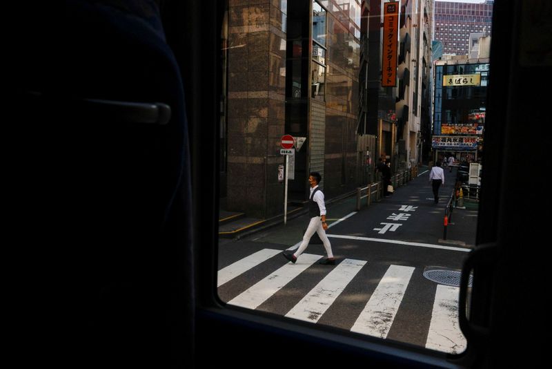 A man crosses a street ahead of the Tokyo 2020