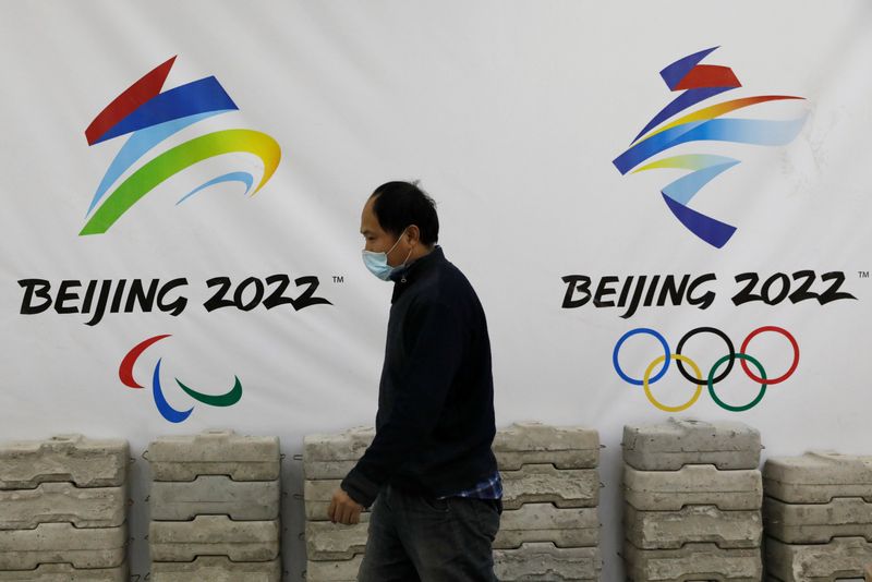 Man walks past a board with logos of 2022 Winter