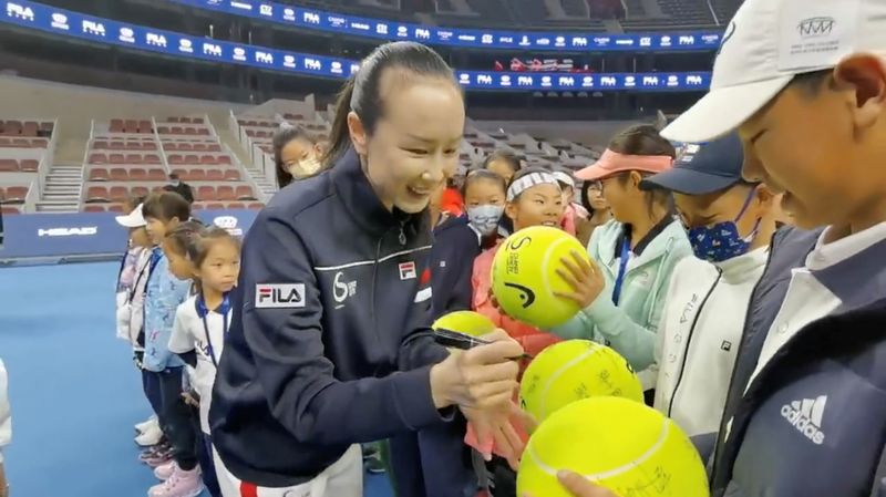 Chinese tennis player Peng Shuai signs large-sized tennis balls at