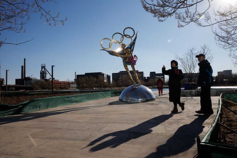 People stand next to a statue featuring the Olympic Rings