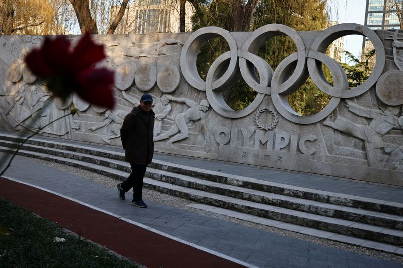 A man walks past a base relief containing the Olympic