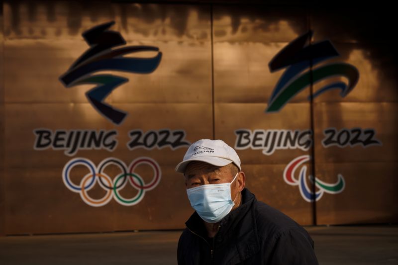 A man walks past the logos of the Beijing 2022