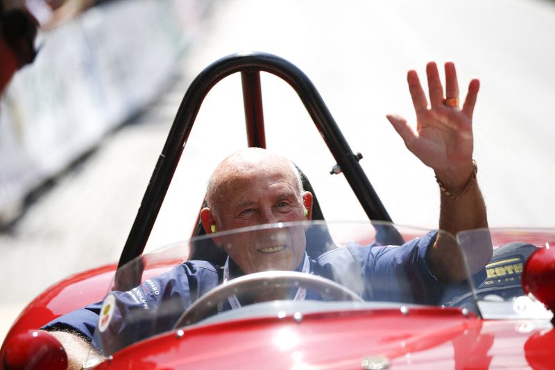 Former English Formula One driver Stirling Moss waves to spectators