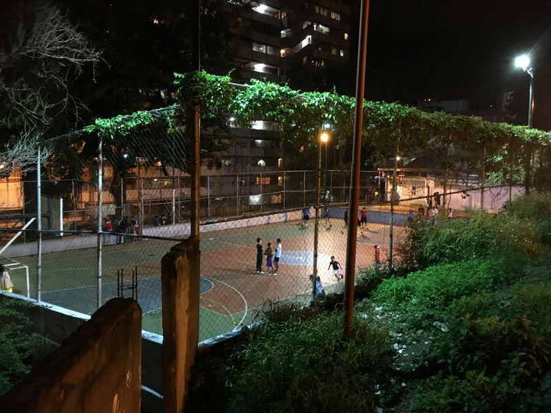 Children play football at a multipurpose court under the floodlights