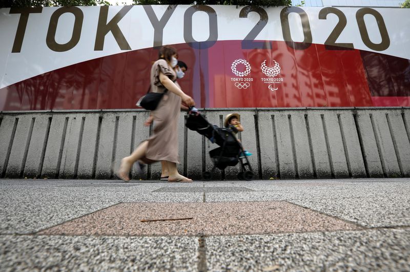 A family walks past an advertisement for Tokyo 2020 Olympic