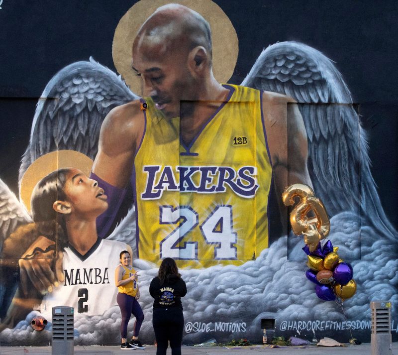 FILE PHOTO: A fan poses by a mural of late