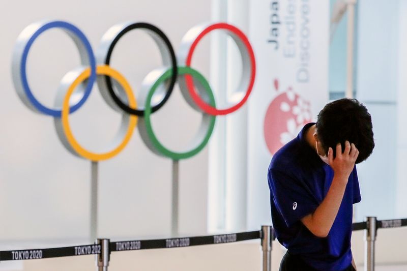 A staff standing in front of Olympic rings reacts while