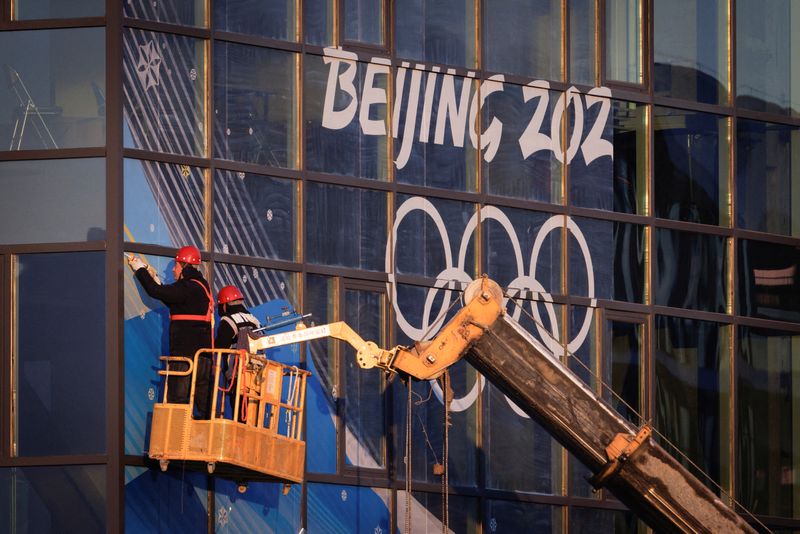 Workers attach signage near Big Air Shougang, a competition venue