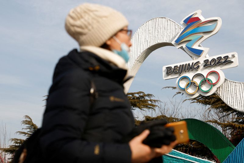 A woman walks past the Beijing 2022 Winter Olympic logo