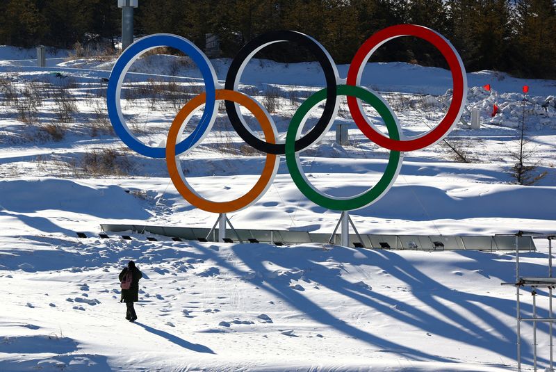 FILE PHOTO: A person walks past the Olympic rings in
