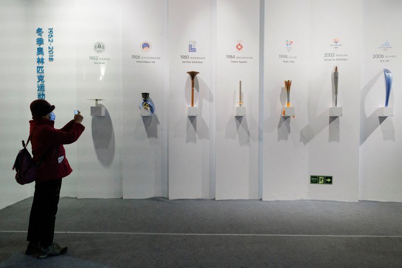 A woman takes pictures of Olympic torches of past Games