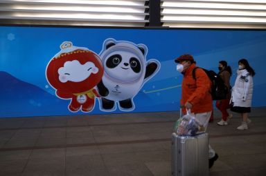 Travellers walk past an image of the Beijing 2022 Winter