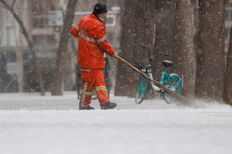 Municipal worker sweeps snow off a street amid snowfall in