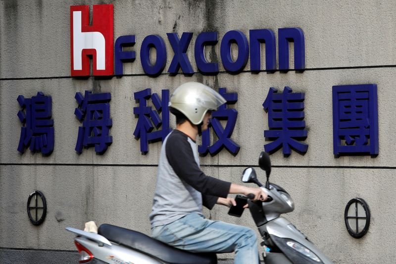FILE PHOTO: A motorcyclist rides past the logo of Foxconn,