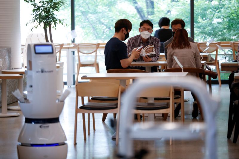 Customers wait at a cafe where a robot that takes