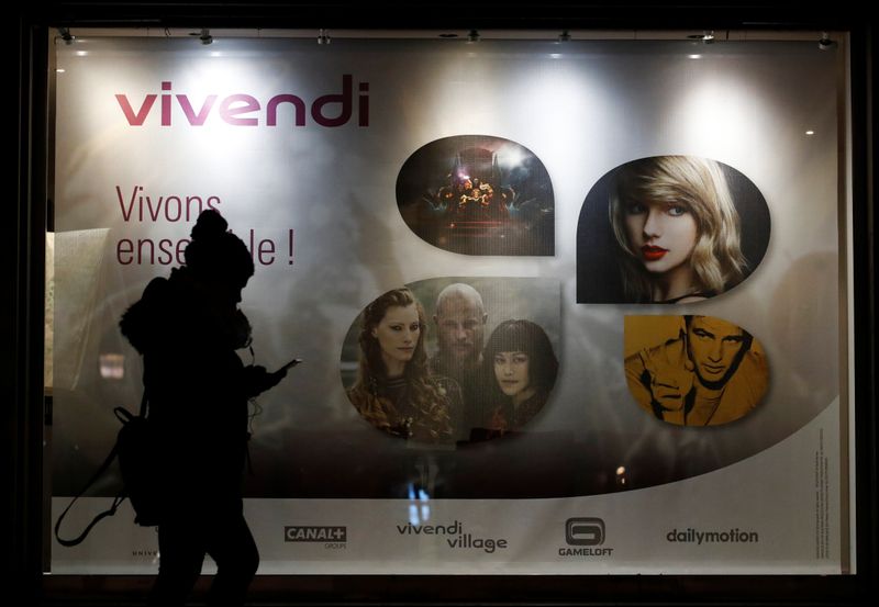 A woman walks pass by a sign of Vivendi at