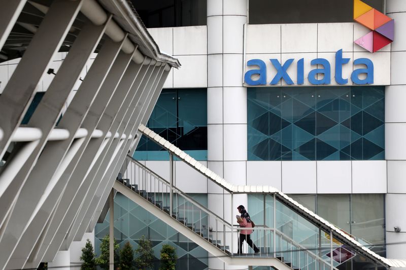 A woman walks past the Axiata headquarters building in Kuala
