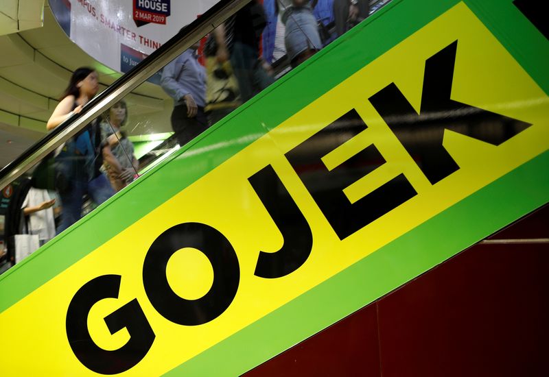 FILE PHOTO: Commuters pass by a Gojek advertisement in Singapore