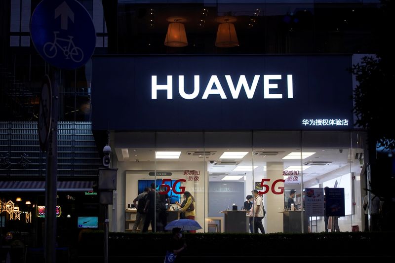 People are seen in a Huawei shop on a street