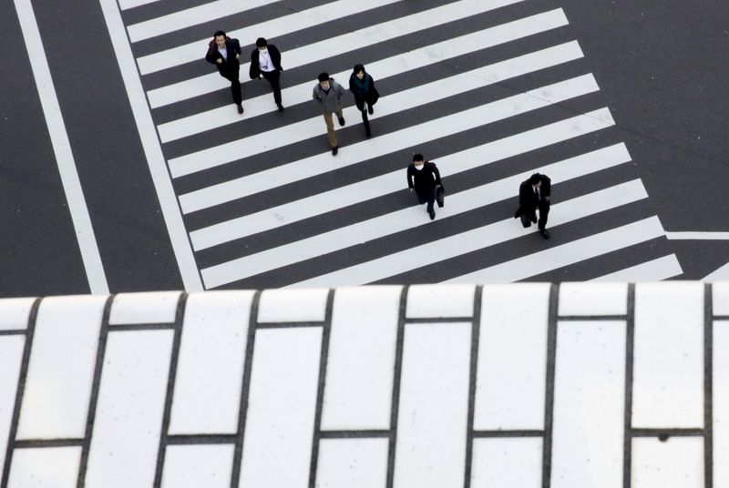 FILE PHOTO: People cross a street in a business district
