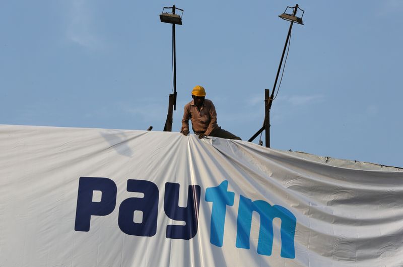 A worker adjusts a hoarding of Paytm, a digital payments