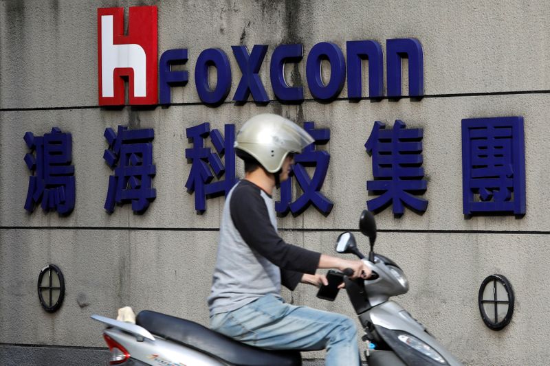 A motorcyclist rides past the logo of Foxconn, the trading