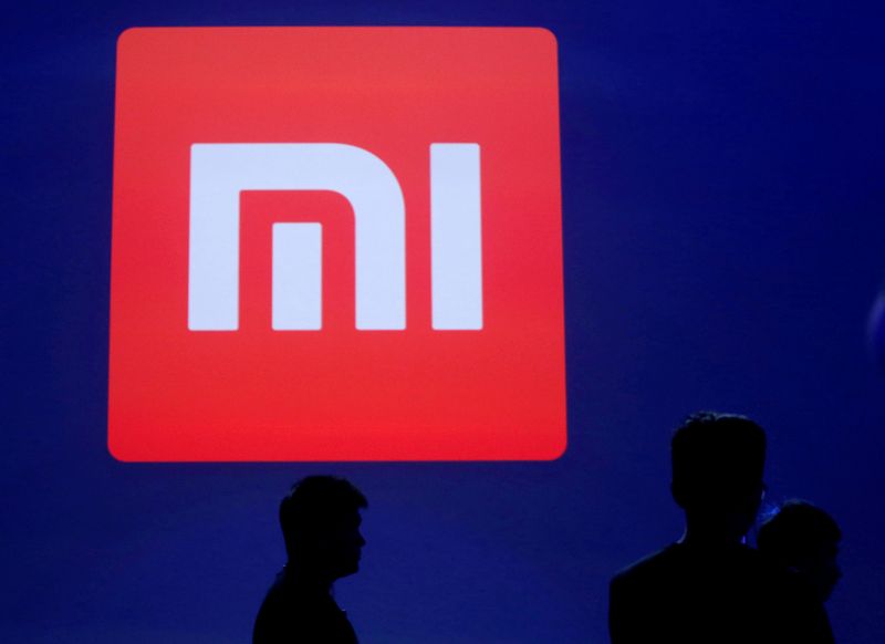 FILE PHOTO: Attendants are silhouetted in front of Xiaomi’s logo