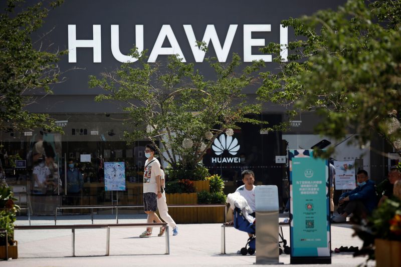 People walk past a Huawei store at a shopping complex