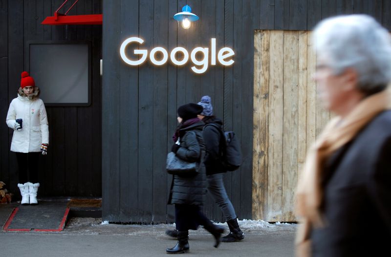 FILE PHOTO:  People walk past the logo of Google