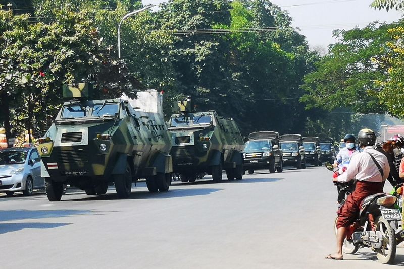 Myanmar Army armored vehicles drive past a street after they