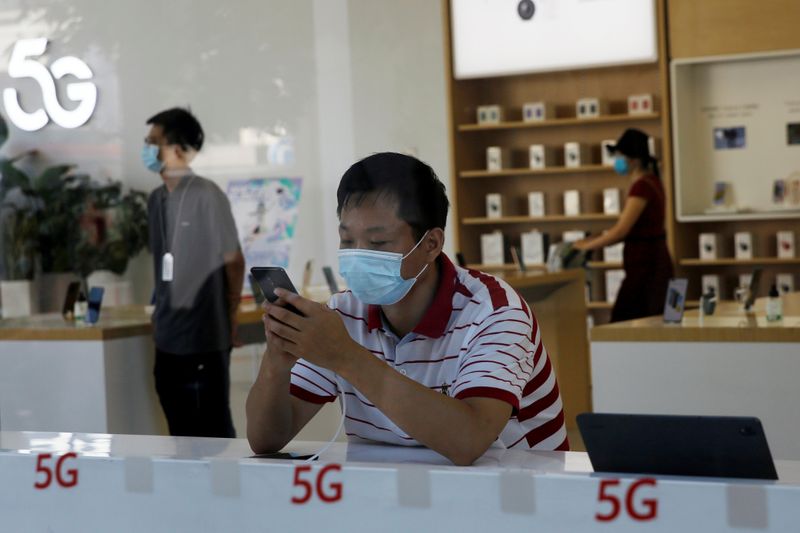 Man checks a mobile phone inside a Huawei store at