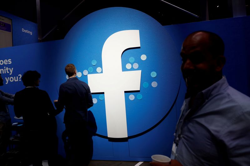 FILE PHOTO: Attendees walk past a Facebook logo during Facebook