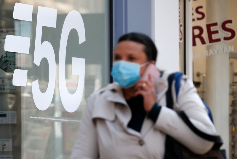 A woman walks past a 5G data network sign at