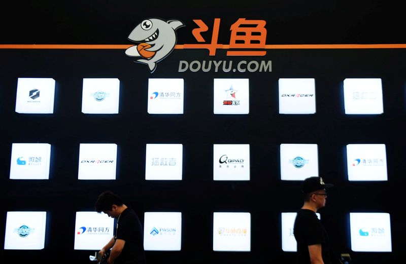 People walk past a booth of live-streaming platform Douyu at