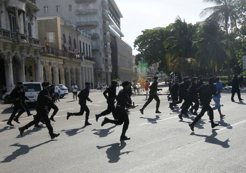 Police run during protests against and in support of the
