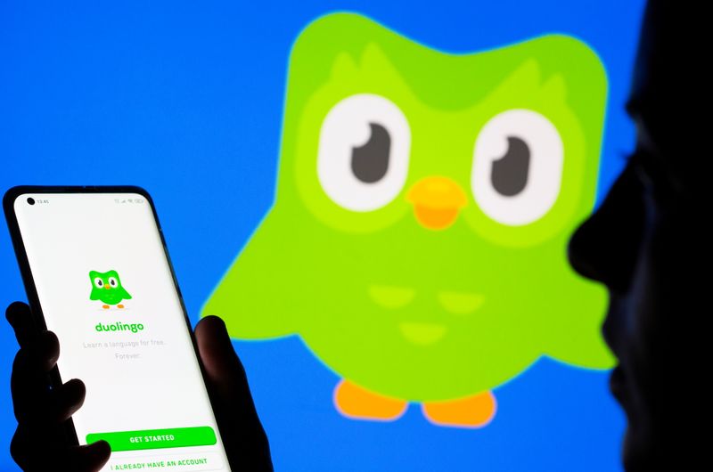 Woman with her smartphone poses in front of displayed Duolingo