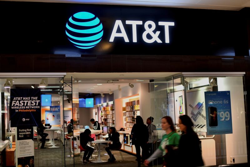 FILE PHOTO: Shoppers walk past an AT&T store at the