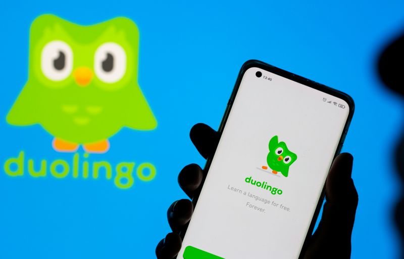 Woman with her smartphone poses in front of displayed Duolingo
