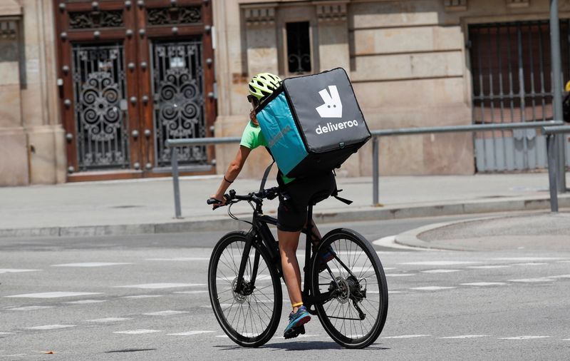 A biker wearing a Deliveroo backpack drives in the central