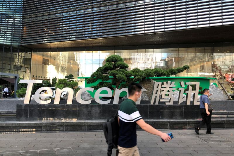 FILE PHOTO: People walk past a Tencent sign at the