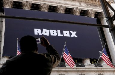 A man photographs a Roblox banner displayed, to celebrate the