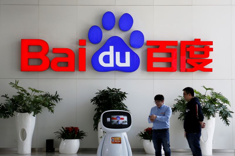 FILE PHOTO: Men interact with a Baidu AI robot near