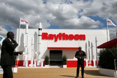 A security officer stands guard in front of a Raytheon