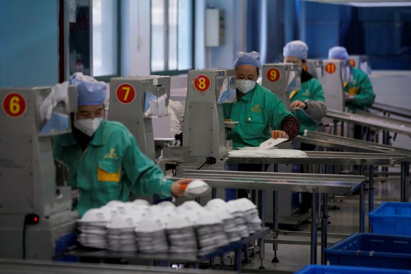 Workers are seen on a production line manufacturing masks at