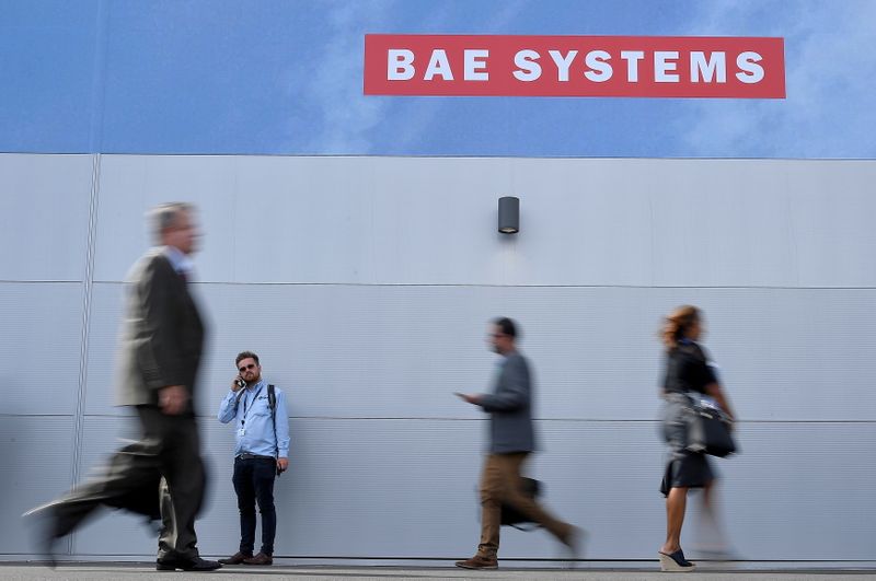 FILE PHOTO: Trade visitors walk past an advertisement for BAE