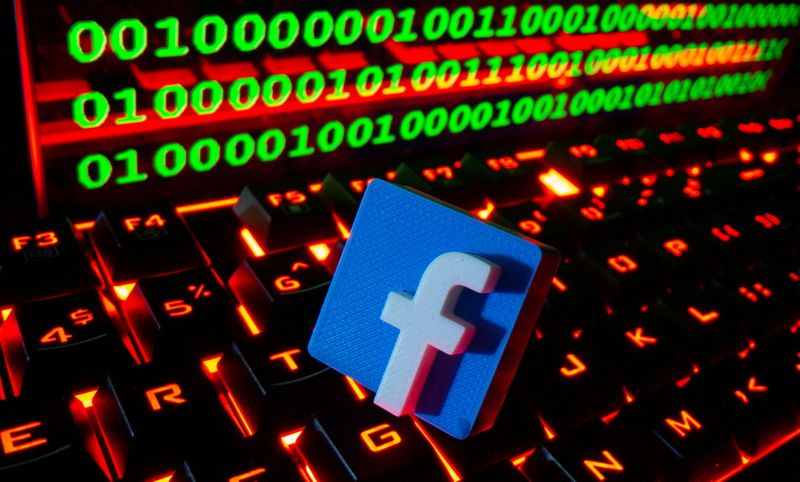 FILE PHOTO: Facebook logo displayed in front of binary code